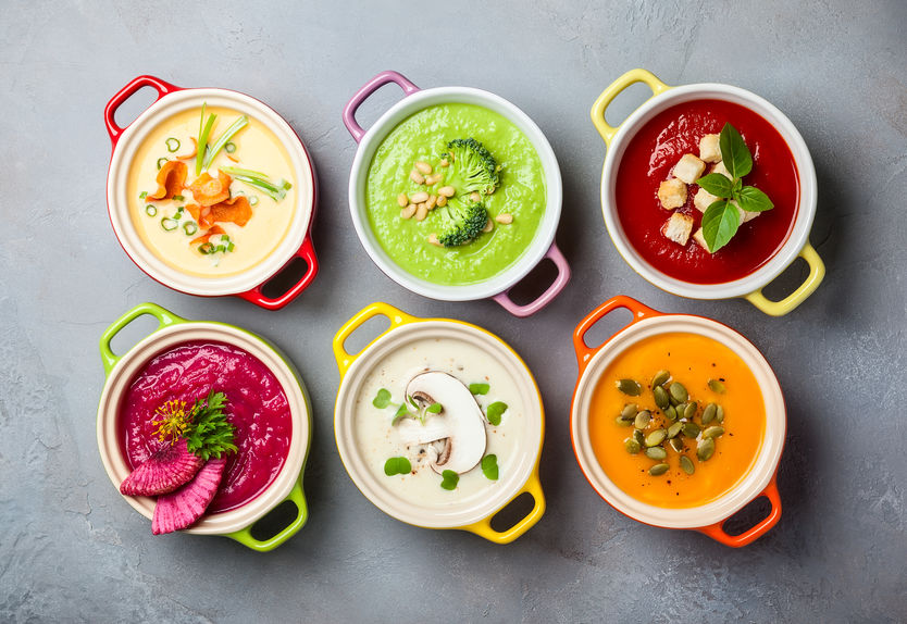 Variety of colorful vegetables cream soups in small pots. Top view. Concept of healthy eating or vegetarian food.