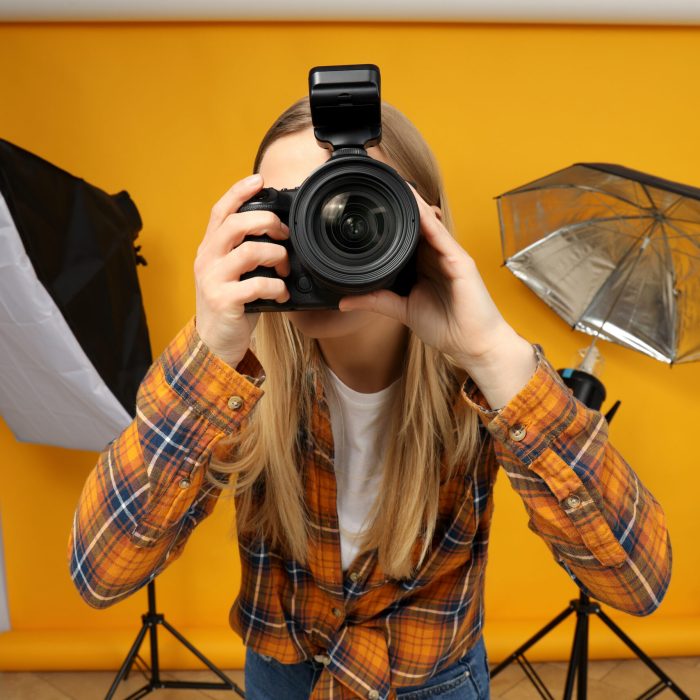 Beautiful girl photographer in the photo studio, on a yellow background.