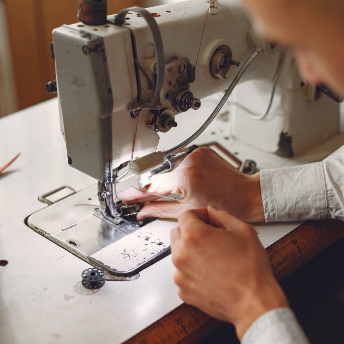 Man working with leather. Professional makes a wallet. Man uses a sewing mashine.